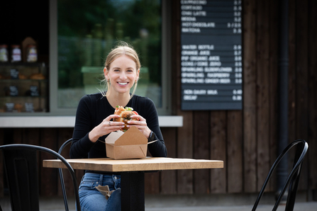 Woman eating sandwich in front of the camley street visitor centre cafe and visitor centre