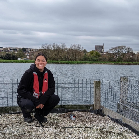 Yasmin, a young adult who is a Keeping it Wild Trainee captured by the water in a life jacket smiling - Carrying out repairs and decoy maintenance on rafts at Walthamstow Wetlands.