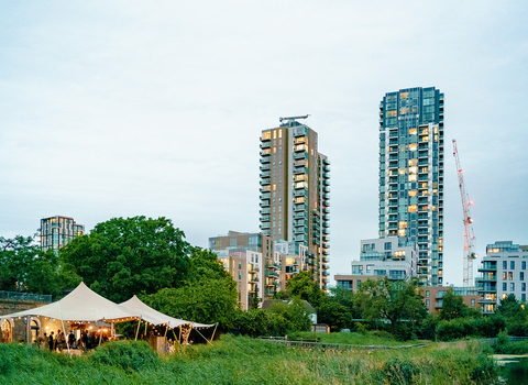 a gazebo erected in a grassy area with large tower block buildings in the background