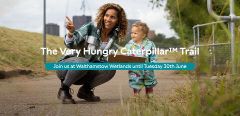 A woman and a small child on the path at Walthamstow Wetlands. Text reads: The Very Hungry CaterpillarTM Trail Join us at Walthamstow Wetlands until Tuesday 30th June