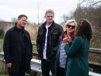 A group of 4 people standing on a bridge talking