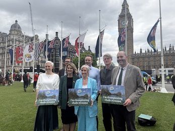 a group of people stand in parliament square holding placards reading 'I'm championing chalk streams'