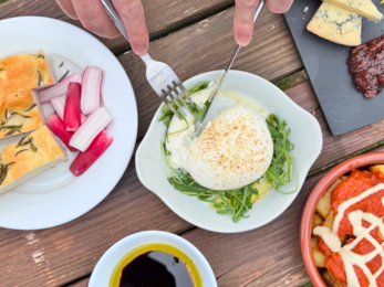 a person using a knife and fork to cut into burrata