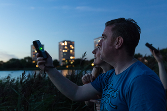 A man holding a bat detector to the sky to listen for Bats at Woodberry Wetlands