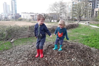Children jumping on bark chippings and leaves