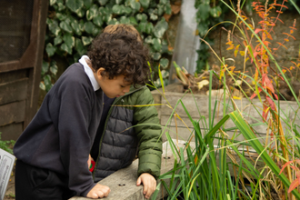 Two children peer into a pond