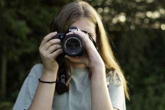 Person holding a camera up to their eye facing the viewer