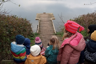 Children sitting by the reservoir at Walthamstow on a chilly day