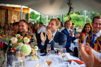 A group of people sat around tables smiling and clapping