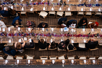 An aerial view of tables lines with flowers with people sitting on either side