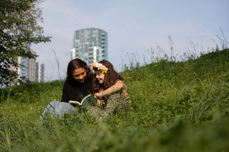Adult reading child a story at Woodberry Wetlands