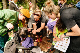 Parents and children looking at an invertebrate