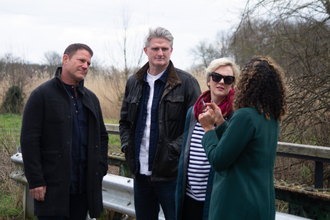 A group of 4 people standing on a bridge talking