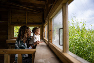 A woman and child looking out from a bird hide into the reedbed