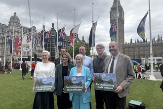 a group of people stand in parliament square holding placards reading 'I'm championing chalk streams'