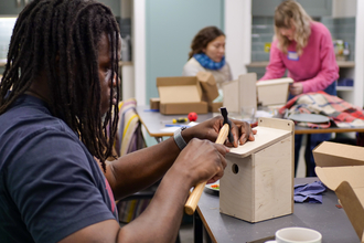 A young person building a birdhouse with a hammer