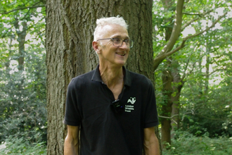 Mathew Frith standing in front of a tree in the woodland of Bramley Bank