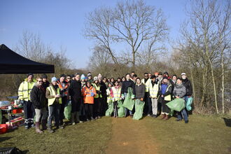 A group of people holding equipment after a litter pick 