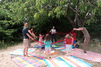 A group of adults and children dancing on picnic blankets