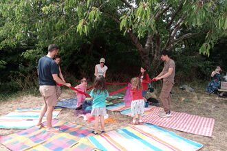 A group of adults and children dancing on picnic blankets 
