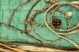 Cordage rope with a bead and pinecone attached on a green tarp.