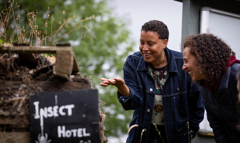 Two people looking and laughing with a bug hotel