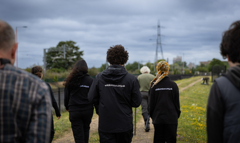 Three Keeping it Wild Trainees in uniform from behind walking at Walthamstow Wetlands.