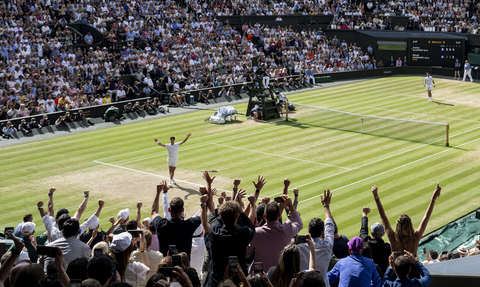 Image of winning tennis player on centre court celebrating with crowd