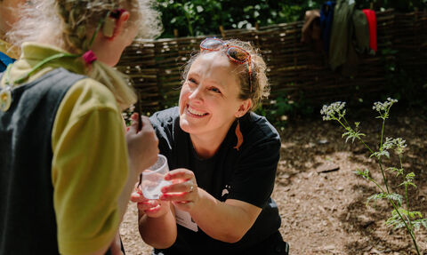 London Wildlife Trust staff member outdoors showing a child a bug in a pot