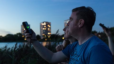 A man holding a bat detector to the sky to listen for Bats at Woodberry Wetlands