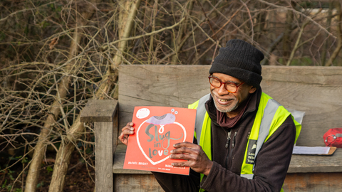 A person holding a red square book that reads A Slug in Love
