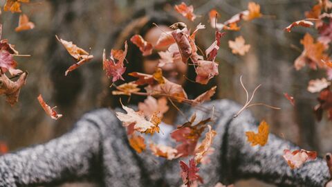 Woman throwing autumn leaves