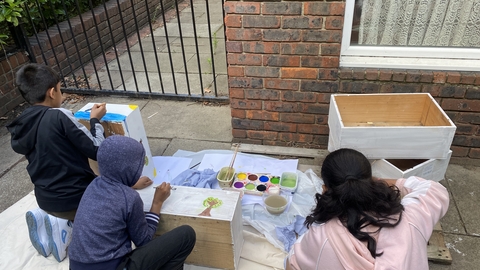 three young people at after school club in Poplar painting planters in preparation for the wildlife garden.