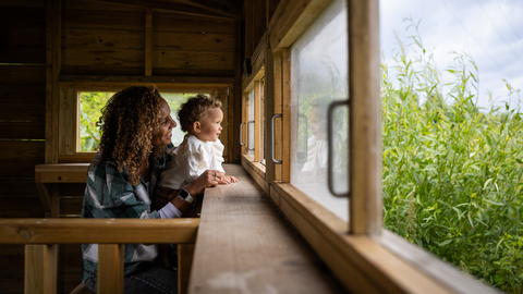 A woman and child looking out from a bird hide into the reedbed