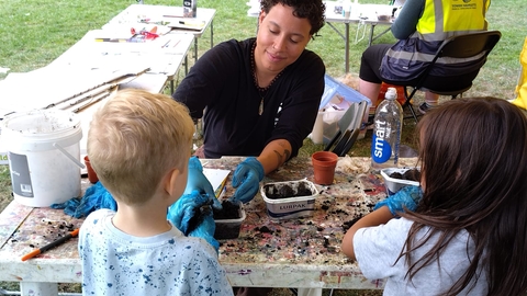 An adult and two children make seed-pot crafts at a table