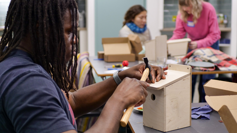 A young person building a birdhouse with a hammer