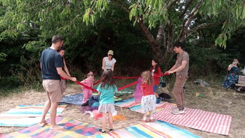 A group of adults and children dancing on picnic blankets 