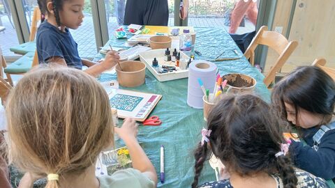 A group of children work on nature scrapbooks around a table