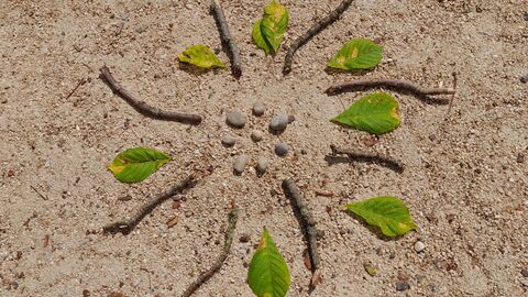 A natural artwork in the form of a mandela, using twigs, leaves and stones in a circular formation 