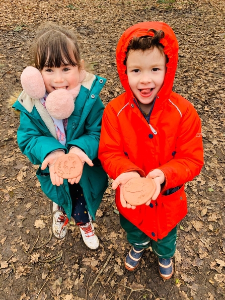 Two children hold up their art outside