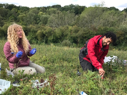 Two people sit on grassland surveying