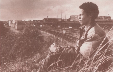 A young Lester Holloway sat by a railway line looking into the distance