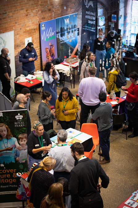 Room full of people, chairs and tables set out with paper and information banners at the Green Jobs Fair