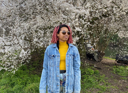 Young person with sunglasses in front of a tree filled with blossom