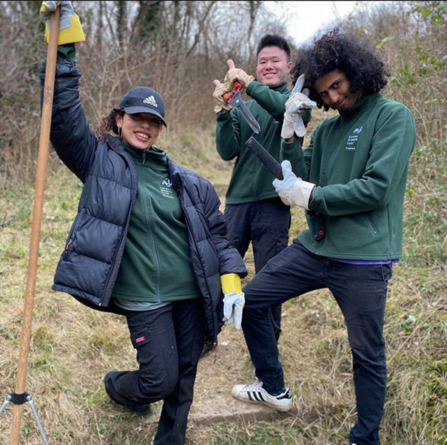 Three young Keeping it Wild trainees smiling whilst working on site