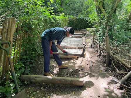 Youth Trainee Naomi using a Mattock to build a path
