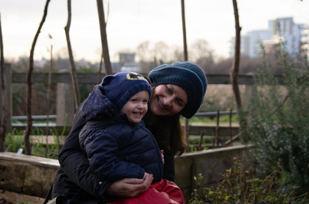 A child sits smiling on the lap of a person who smiles looking at the childs face