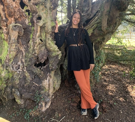 A person stood leaning against a large tree