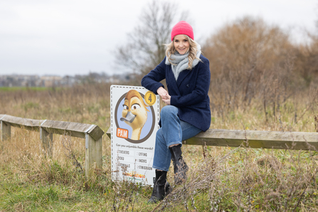 Presenter Helen Skelton sat on a fence with a Migration Trail point at Walthamstow Wetlands