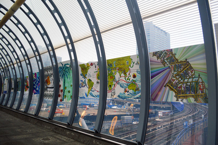 An art mural created on glass panels of a train station walking tunnel.
